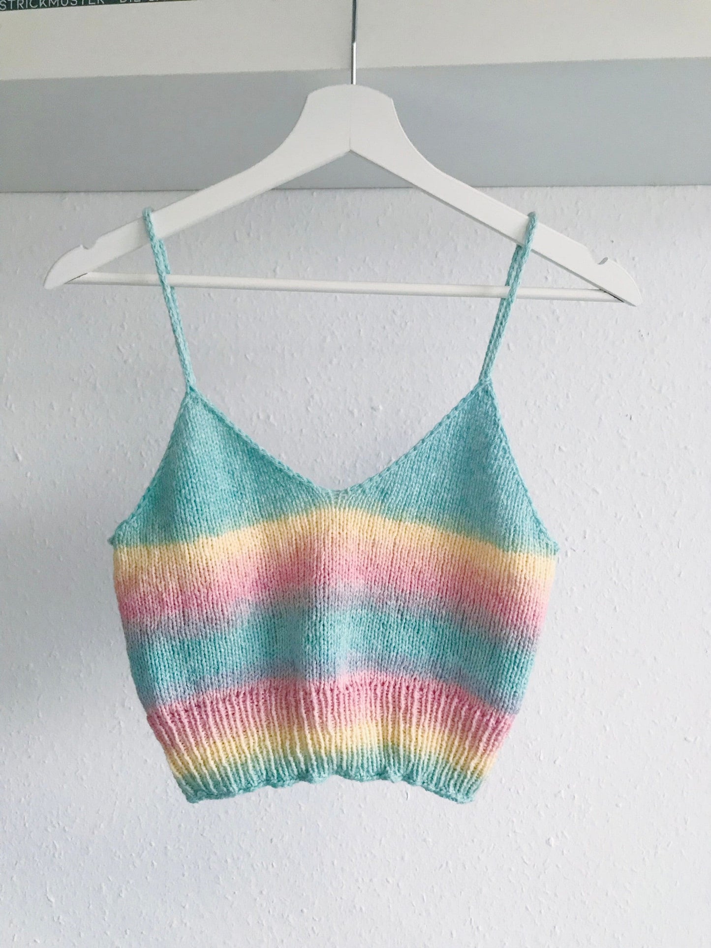 Pastel striped knitted camisole on a hanger