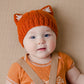Orange knitted kitty ears beanie worn by a baby