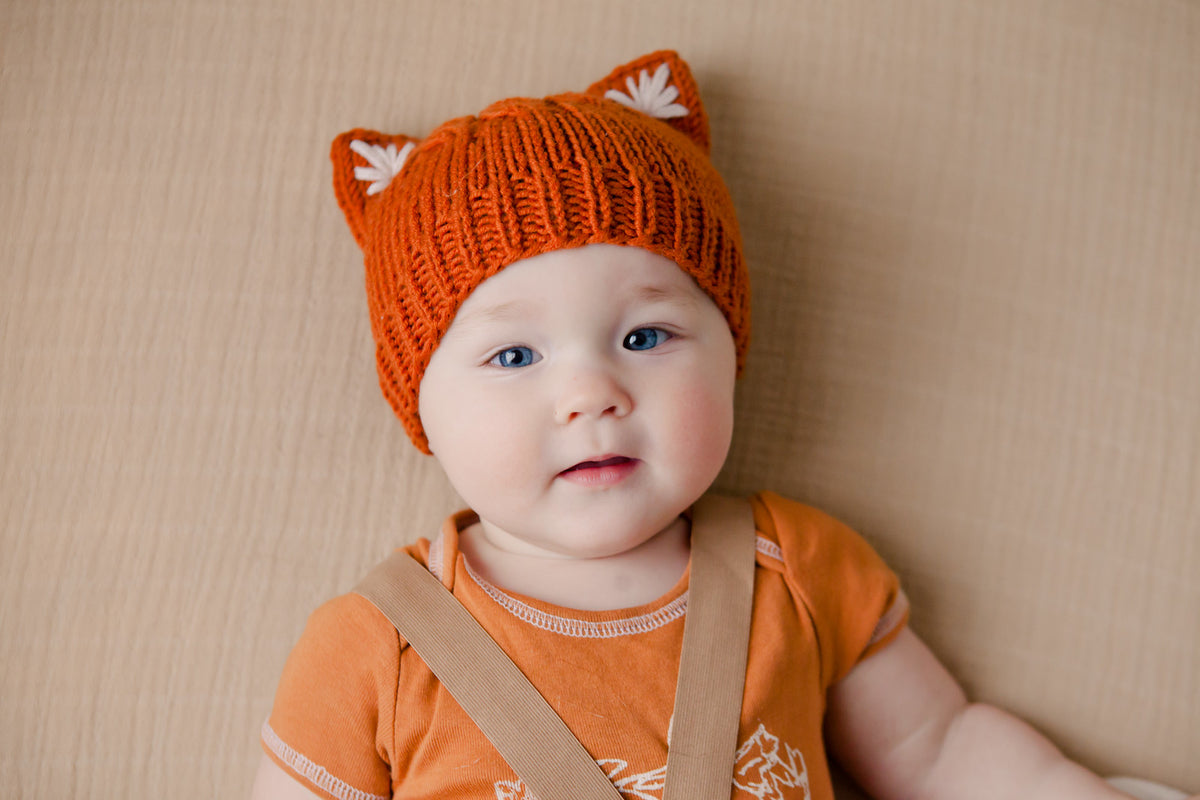 Orange knitted kitty ears beanie worn by a baby