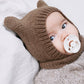 Brown knitted bear-ear hood with a ribbed face band worn by a baby