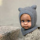 Grey bear-ear hood worn outdoors, showing its face opening and longer neck warmer