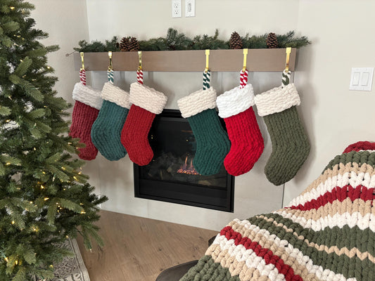 Finger Knit Fireside Stocking in several colours displayed above a fireplace